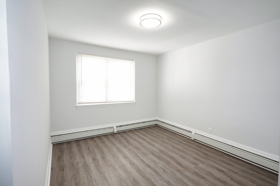 open bedroom with wood floor and white walls