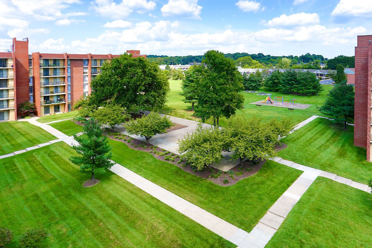 grass area outside of building including trees and walking paths